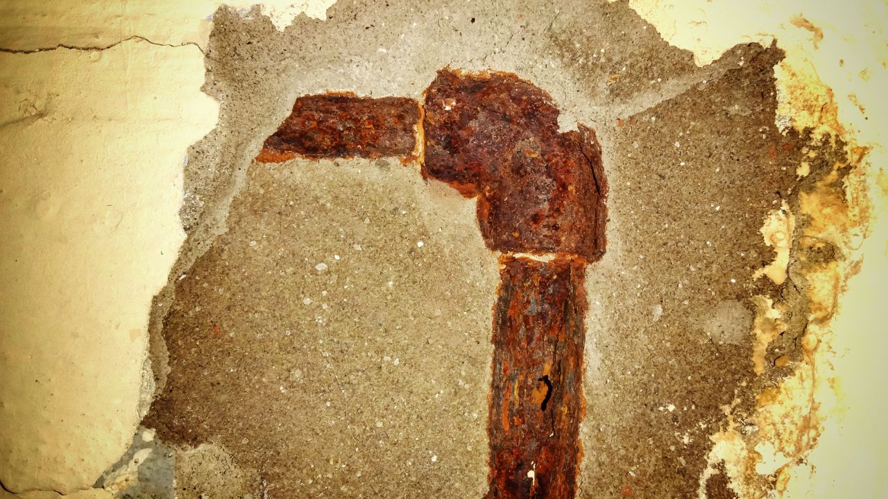 Image of rusted water pipe that runs in a slab of concrete.